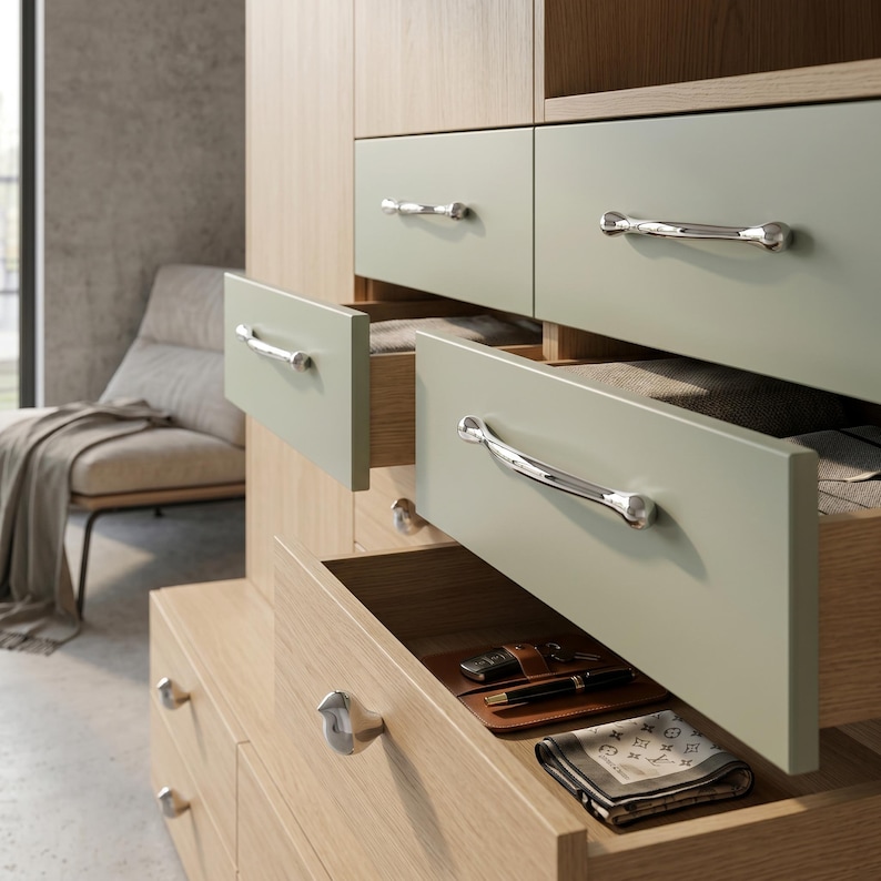 Puede incluir: C&oacute;moda de madera clara con varios cajones, algunos abiertos. Los cajones son de color verde suave y tienen tiradores plateados. Contenido: cartera, bol&iacute;grafo, llaves y pa&ntilde;uelo estampado. La c&oacute;moda est&aacute; en una habitaci&oacute;n bien iluminada.