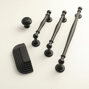 May include: A collection of matte black cabinet hardware, including a knob, three pull handles, and a cup pull. The handles have a decorative design with a ball and a textured base. The hardware is designed for use on cabinets and drawers.