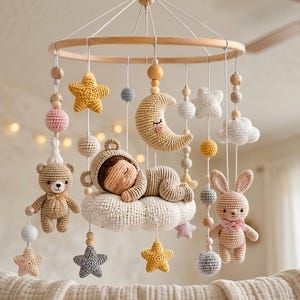 May include: A nursery mobile featuring crocheted figures including a sleeping baby on a cloud, a teddy bear, a rabbit, a crescent moon, stars, and clouds. The items are suspended from a circular wooden frame by white strings with wooden beads.