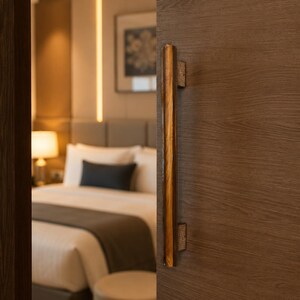 May include: A vertical door handle with a polished, dark wood finish and textured, metallic mounting brackets attached to a wood-grain door panel. The handle features a smooth, reflective surface that contrasts with the matte finish of the door.