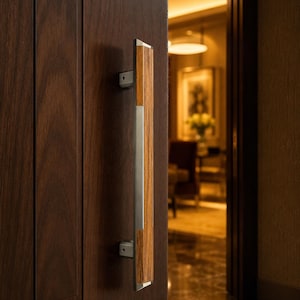 May include: A vertical door handle mounted on a dark brown wooden door. The handle features a central brushed metal strip flanked by two vertical wood grain panels, secured to the door by two rectangular metal brackets at the top and bottom.