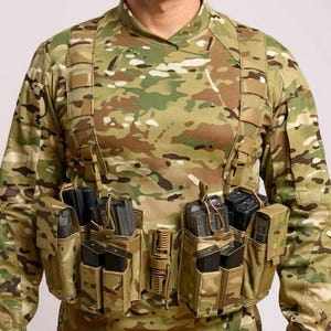 May include: Camouflage tactical chest rig with multiple magazine pouches. The rig is tan and brown with black magazines. The person is wearing a camouflage long-sleeve shirt.