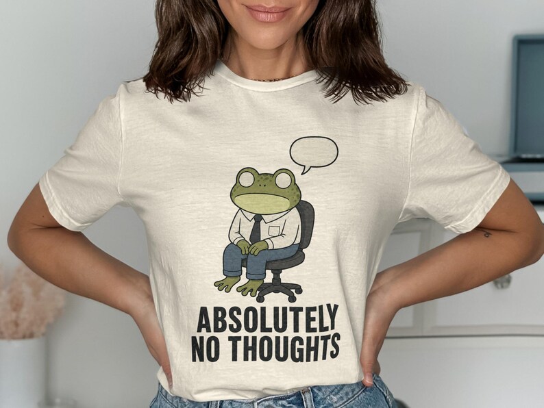 Cream t-shirt with a cartoon frog in a chair, speaking bubble, and "ABSOLUTELY NO THOUGHTS" text.