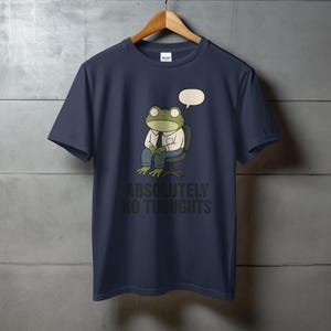Dark blue t-shirt with a cartoon frog wearing a shirt and tie, sitting in a chair, with text "ABSOLUTELY NO THOUGHTS".