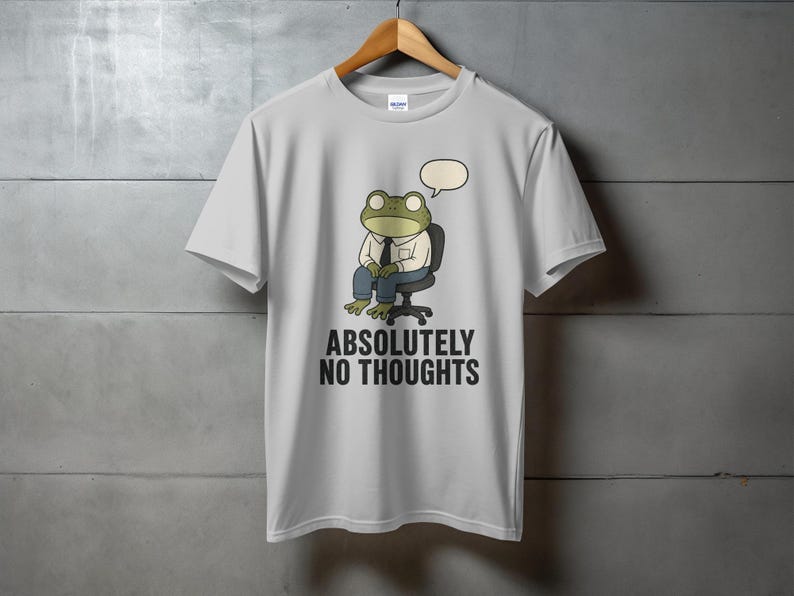 Light gray t-shirt with frog character sitting in chair, text "ABSOLUTELY NO THOUGHTS".