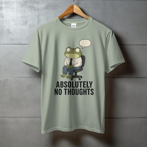 Light green t-shirt with cartoon frog sitting in a chair, "ABSOLUTELY NO THOUGHTS" text.