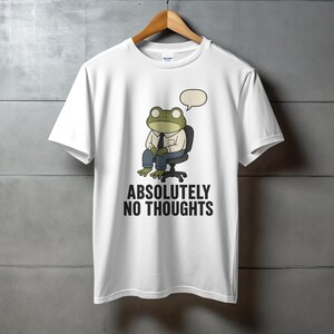 White t-shirt with graphic of a frog wearing a shirt and tie, sitting in a chair, with "ABSOLUTELY NO THOUGHTS" text.