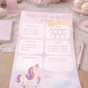 May include: A light purple invitation with the text "Magst du dich zum Spielen treffen?" and a unicorn illustration. The invitation includes sections for meeting location, time, and contact information. A pink pen rests on the table.