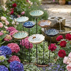 Può includere: Un set di sette abbeveratoi per uccelli in ceramica a forma di fiore su sottili picchetti di metallo. Ogni ciotola presenta una finitura smaltata unica nei toni del blu, verde, bianco e marrone. Una ciotola bianca contiene piccoli ciottoli di vetro.