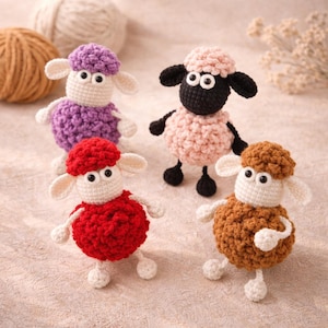 Puede incluir: Cuatro ovejas de ganchillo hechas a mano en varios colores: morado, rosa, rojo y marrón. Cada oveja tiene cara, orejas y patas blancas, con detalles en negro o del mismo color. Los juguetes están sobre un fondo suave y neutro.