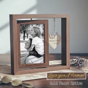 Könnte beinhalten: Ein hellbrauner Holzfotorahmen mit einem Schwarz-Weiß-Foto von Mutter und Kind. Der Rahmen trägt den Text "Love you, Mama!" und einen herzförmigen Anhänger mit der Aufschrift "Love you Mom - Emily".