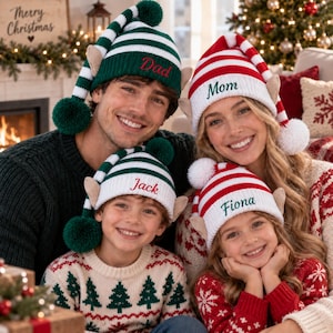 May include: Four knit elf hats with pom-poms and felt ears. Two hats are green and white striped with red embroidery reading Dad and Jack. Two hats are red and white striped with green embroidery reading Mom and Fiona. The hats have long tails.