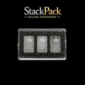 Puede incluir: Tres lingotes de plata de 1 gramo en una funda de plástico transparente. Cada lingote presenta un diseño de hoja de arce y el texto "1 GRAM 999 FINE SILVER". La funda está sobre un fondo negro, con el logotipo "StackPack" arriba.