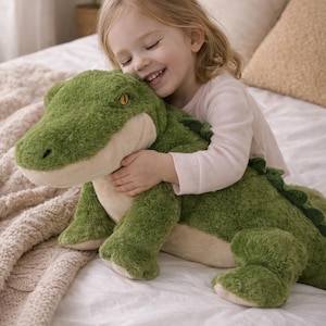 May include: A large, plush green alligator toy with a cream-coloured belly and accents. The toy has a textured, fuzzy appearance and is being hugged. The alligator has yellow eyes and a row of green spines down its back.