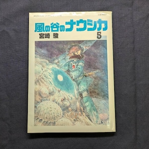 May include: A vintage Japanese manga book titled "Nausica&auml; of the Valley of the Wind" with a vibrant illustration of a character in a blue outfit. The cover features Japanese text and the number 5.