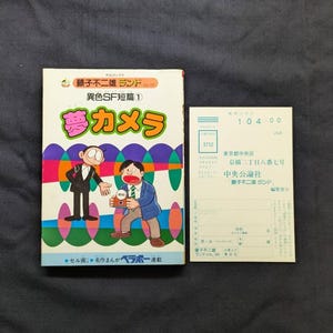 May include: A vintage Japanese comic book titled "Yume Kamera" with colorful illustrations of cartoon characters. The cover features Japanese text and a small white card with more text.