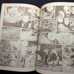 May include: An open book displaying manga panels with detailed illustrations in sepia tones. The panels depict scenes of explosions, skeletal figures, and a young girl. The artwork has a vintage, hand-drawn aesthetic.
