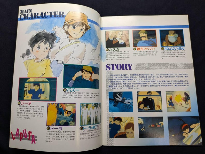 May include: A printed book page featuring illustrations and Japanese text from the film Laputa: Castle in the Sky. The layout includes a Main Character section with character portraits and a Story section with multiple small scene panels.