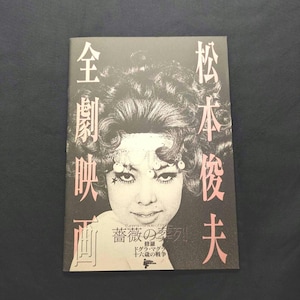 May include: A rectangular book cover featuring a high-contrast black and white portrait of a person with voluminous hair and a star-shaped mark on their cheek. The cover includes pink Japanese text and the English title Funeral Parade of Roses.