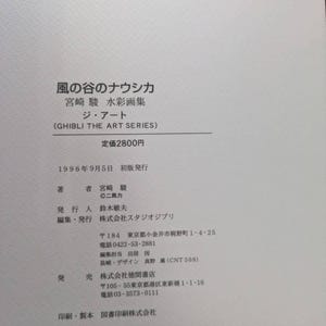 Pu&ograve; includere: Un libro bianco con testo giapponese, tra cui il titolo "Nausica&auml; della Valle del Vento" e "Ghibli The Art Series". La copertina presenta anche il prezzo e i dettagli della pubblicazione. Il libro &egrave; stato stampato nel 1996.