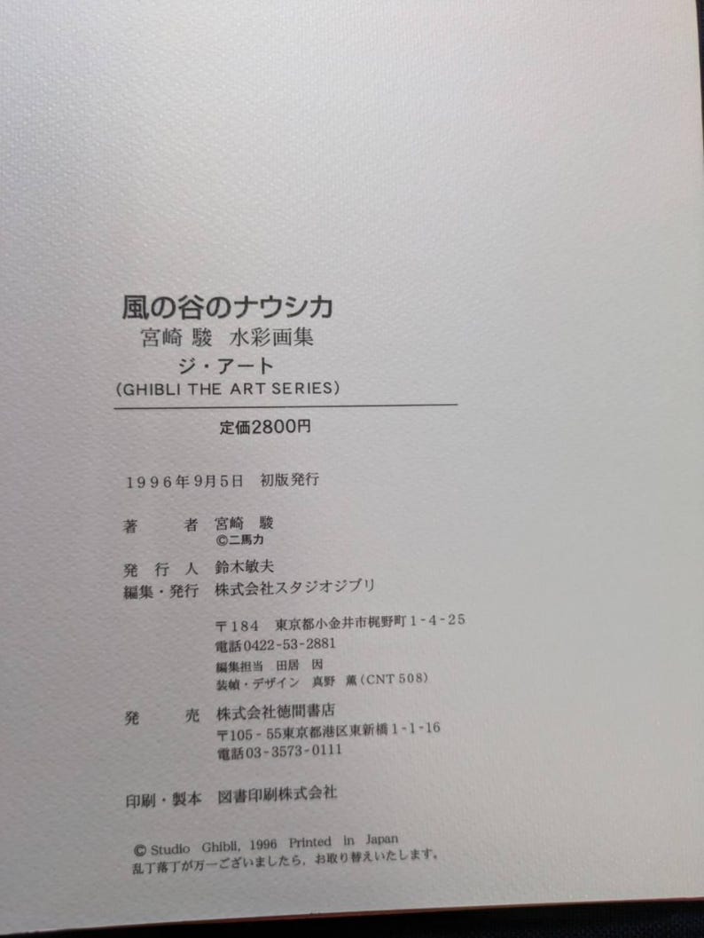 Pu&ograve; includere: Un libro bianco con testo giapponese, tra cui il titolo "Nausica&auml; della Valle del Vento" e "Ghibli The Art Series". La copertina presenta anche il prezzo e i dettagli della pubblicazione. Il libro &egrave; stato stampato nel 1996.