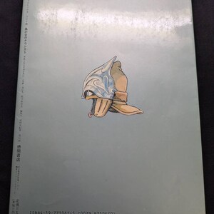 May include: A book cover with a light blue background featuring an illustration of a helmet and boot. The helmet is silver and blue, and the boot is tan. Japanese text is printed on the left side and bottom of the cover.