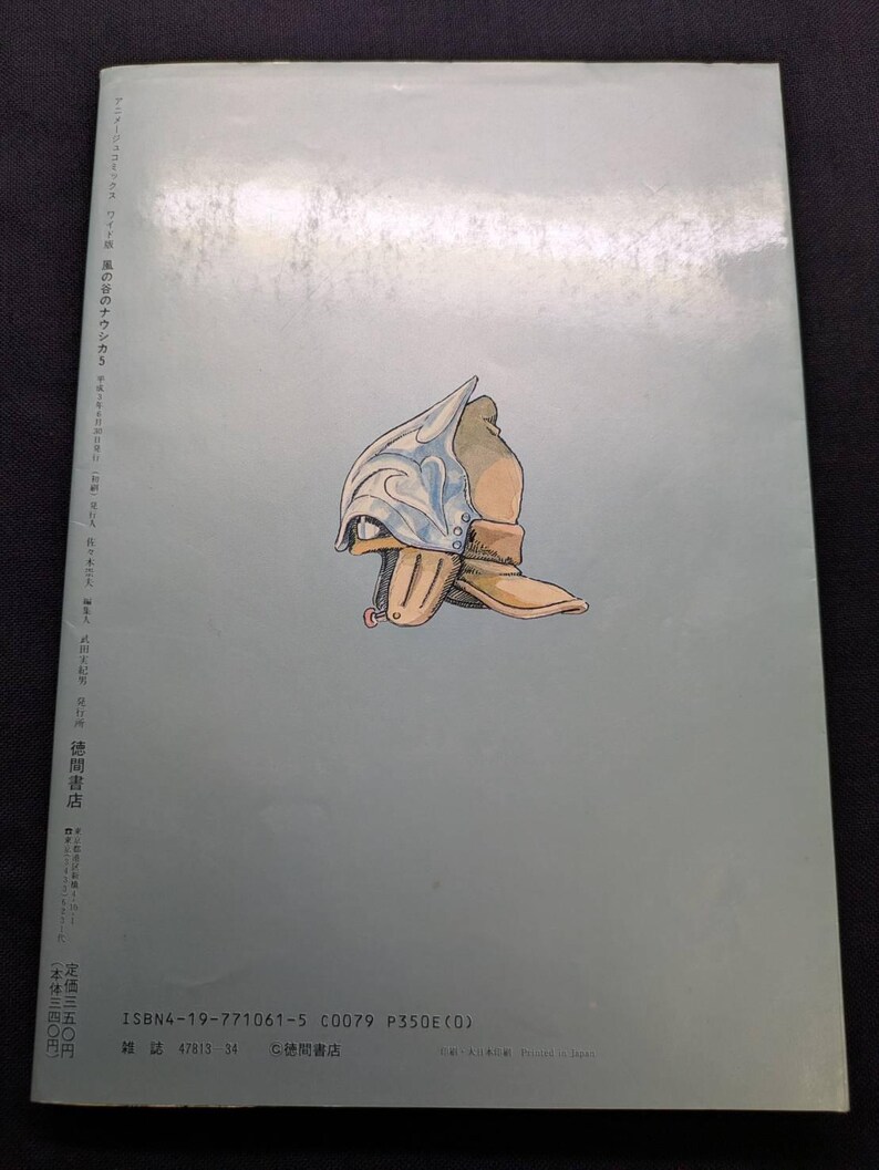 May include: A book cover with a light blue background featuring an illustration of a helmet and boot. The helmet is silver and blue, and the boot is tan. Japanese text is printed on the left side and bottom of the cover.