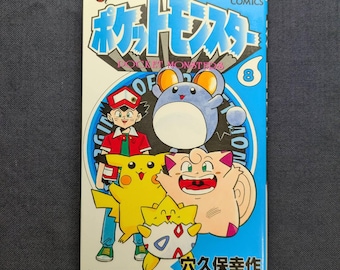 May include: A Japanese manga book titled "Pocket Monsters" with a blue and white cover. The cover features cartoon characters including Pikachu and a blue mouse-like creature. The number 8 is visible on the cover.
