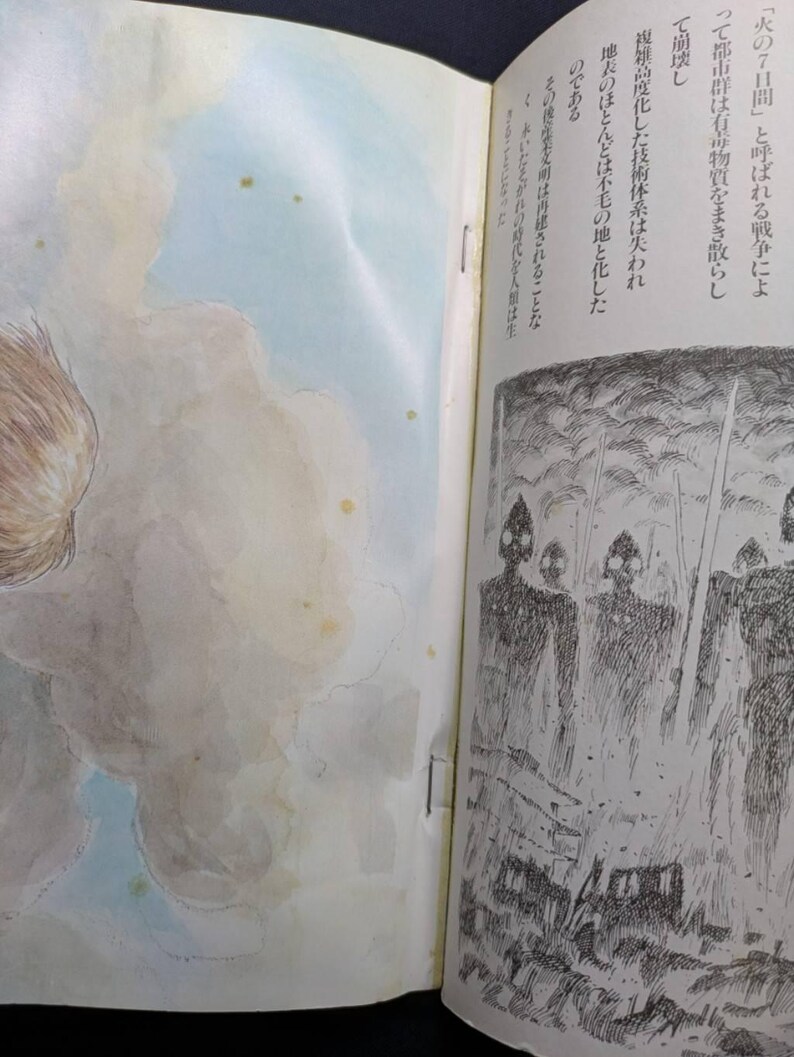 May include: An open book with illustrations and Japanese text. The left page features a watercolor painting of a cloudy sky with light blue and yellow hues. The right page has a black and white illustration of figures with helmets and swords.