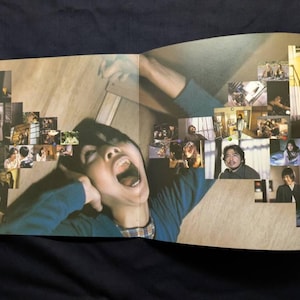 以下が含まれることがあります： 開いた本の見開きページ。画像のコラージュと叫んでいる人物が写っています。人物は青い長袖シャツを着ています。コラージュには様々なシーンや人々が含まれています。