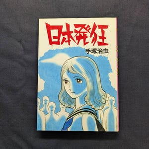 May include: A vintage Japanese manga book with a white cover featuring a young woman with blue hair and a sailor uniform. The title is in red Japanese characters. The background is blue with white figures.