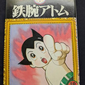 May include: Astro Boy manga volume 18. The cover features a colorful illustration of Astro Boy pointing upwards, framed in gold. The title is in Japanese characters, with additional text at the top.