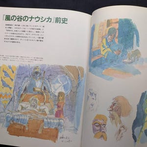 Pu&ograve; includere: Libro aperto con testo giapponese e illustrazioni ad acquerello. Le illustrazioni raffigurano scene e schizzi di personaggi di un film d'animazione. Le pagine sono bianche con il testo e le illustrazioni a colori.