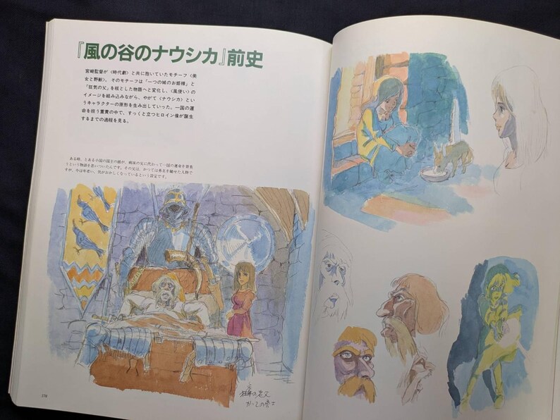Pu&ograve; includere: Libro aperto con testo giapponese e illustrazioni ad acquerello. Le illustrazioni raffigurano scene e schizzi di personaggi di un film d'animazione. Le pagine sono bianche con il testo e le illustrazioni a colori.