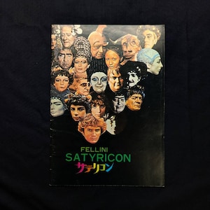 以下が含まれることがあります： フェリーニ・サテリコンの長方形の映画ポスター。黒い背景に様々な登場人物のポートレートがコラージュされています。緑色の文字で「FELLINI SATYRICON」と書かれ、その下にピンク、黄色、青の日本語の文字が印刷されています。