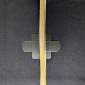 May include: A stack of book pages with a light tan color, held upright by a black book stand. The pages are slightly angled, revealing the edges. The background is a dark blue fabric.