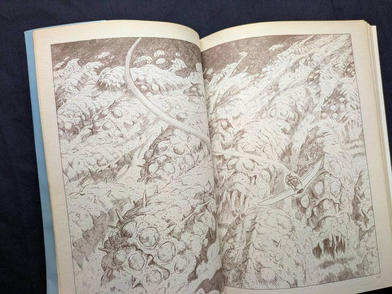 May include: An open book with a detailed pen and ink illustration. The artwork depicts a surreal landscape with organic, textured forms and a weapon. The illustration is in shades of brown and white, creating a stark contrast.