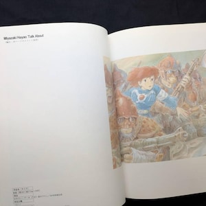 Pu&ograve; includere: Un libro aperto con un'illustrazione colorata. L'immagine raffigura una ragazza dai capelli rossi in un abito blu, circondata da figure in armatura. Il testo "Miyazaki Hayao Talk About" &egrave; visibile nella parte superiore della pagina sinistra.