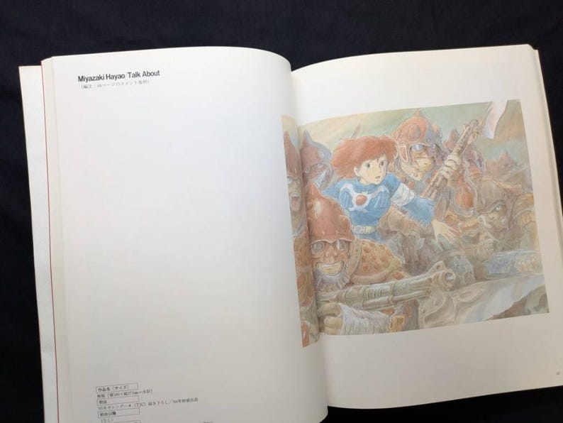 Pu&ograve; includere: Un libro aperto con un'illustrazione colorata. L'immagine raffigura una ragazza dai capelli rossi in un abito blu, circondata da figure in armatura. Il testo "Miyazaki Hayao Talk About" &egrave; visibile nella parte superiore della pagina sinistra.
