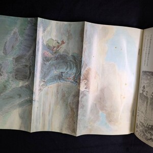 May include: Open book with illustrations. One illustration depicts a figure in a green helmet and blue clothing, possibly a soldier, in a mountainous landscape. The other illustration shows a group of figures with helmets and spears.