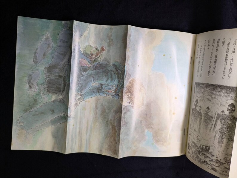 May include: Open book with illustrations. One illustration depicts a figure in a green helmet and blue clothing, possibly a soldier, in a mountainous landscape. The other illustration shows a group of figures with helmets and spears.