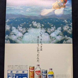 May include: A vintage advertisement poster featuring a sky scene with clouds and a flying vehicle. The text includes AJINOMOTO and Japanese characters. At the bottom, four beverage containers are displayed: a gold can, a clear bottle, a silver can, and a clear bottle with a blue cap.