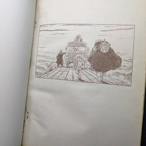 May include: An open book with a black and white illustration. The illustration depicts a scene with figures on a wooden structure, including a person in a cloak and a person running. A decorative object is in the center.