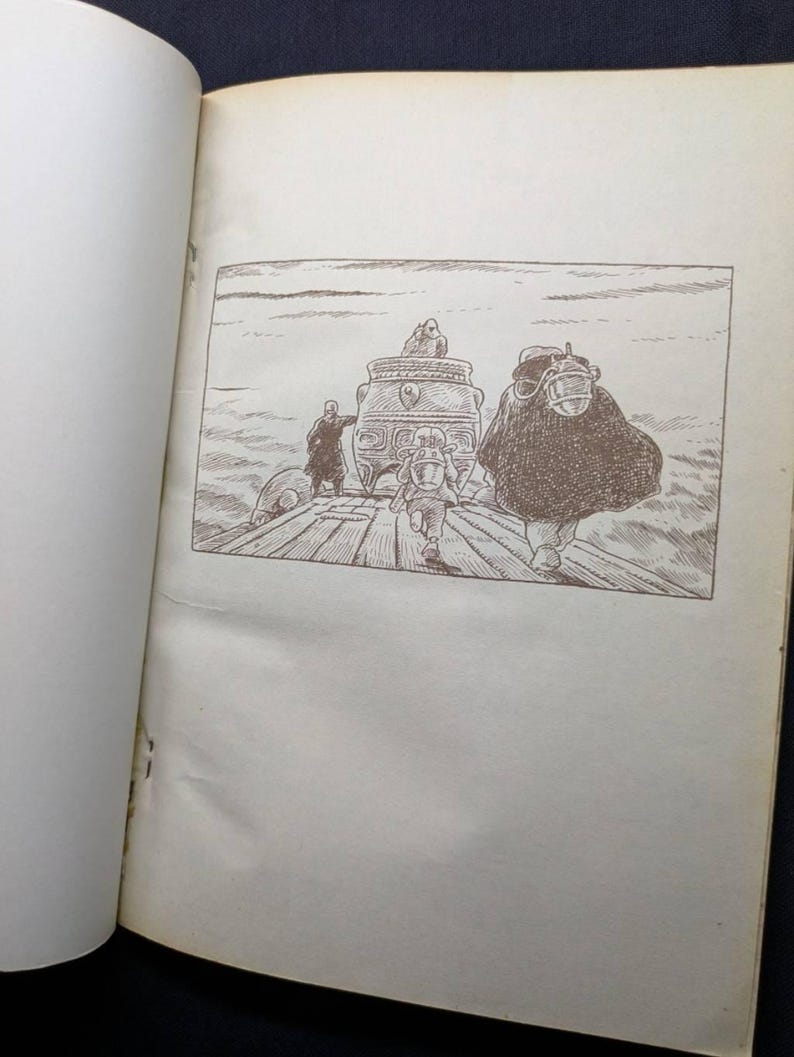 May include: An open book with a black and white illustration. The illustration depicts a scene with figures on a wooden structure, including a person in a cloak and a person running. A decorative object is in the center.