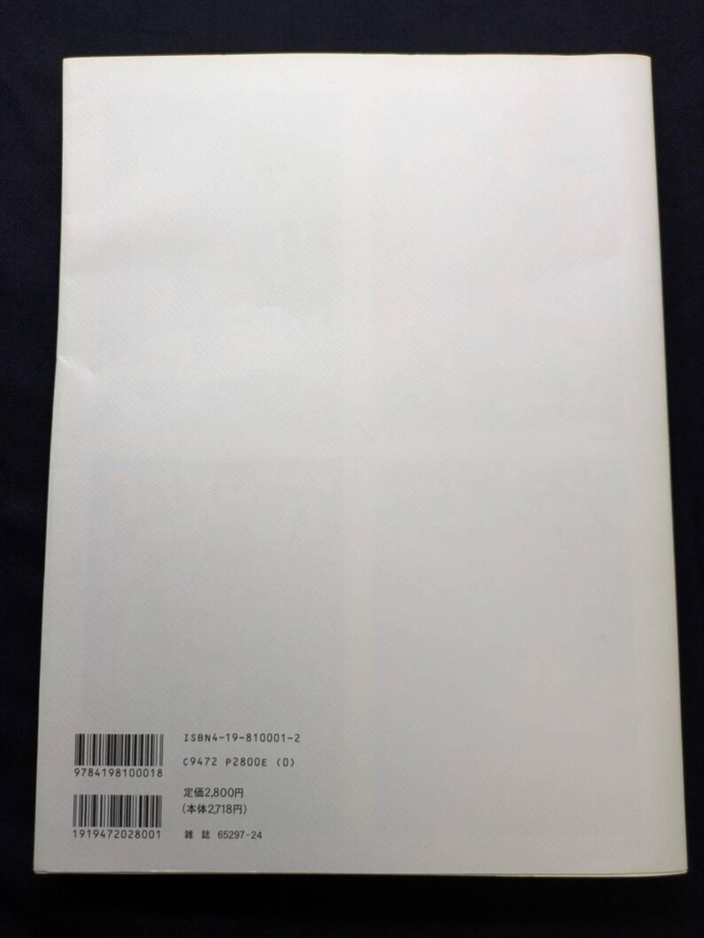 Pu&ograve; includere: Un libro bianco con testo e un codice a barre in basso a sinistra. Il testo include un ISBN, prezzo e altri caratteri giapponesi. La copertina del libro &egrave; semplice e leggermente strutturata.