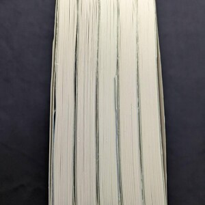 Pode incluir: Uma pilha de cinco livros com p&aacute;ginas brancas e bordas verde claro. As lombadas n&atilde;o s&atilde;o vis&iacute;veis e os livros est&atilde;o dispostos verticalmente sobre um fundo escuro. As p&aacute;ginas est&atilde;o ligeiramente amareladas.