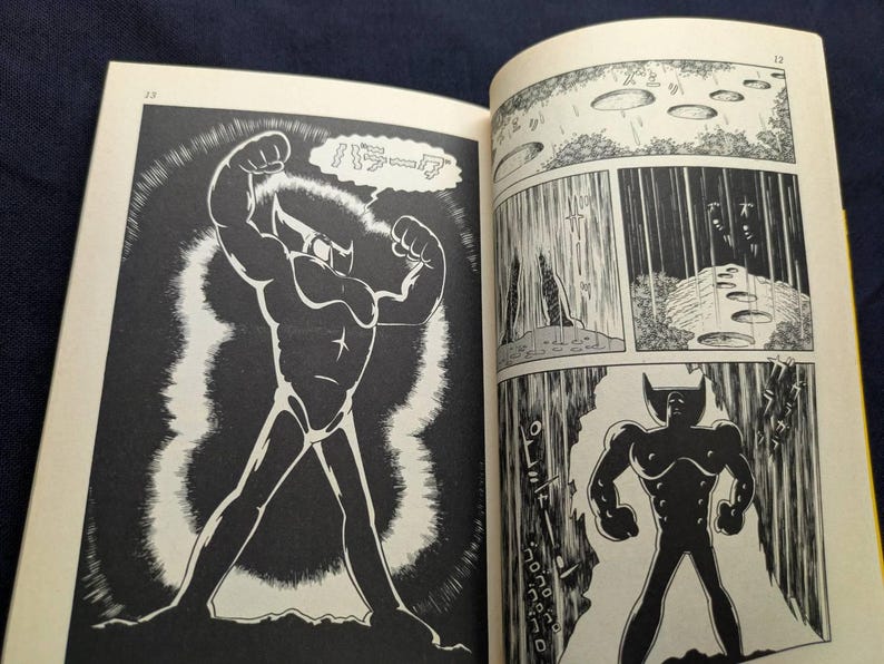 May include: A black and white comic book illustration featuring a muscular figure with a horned head and a star on the chest. The figure is flexing its arms. The comic book is open, displaying multiple panels.