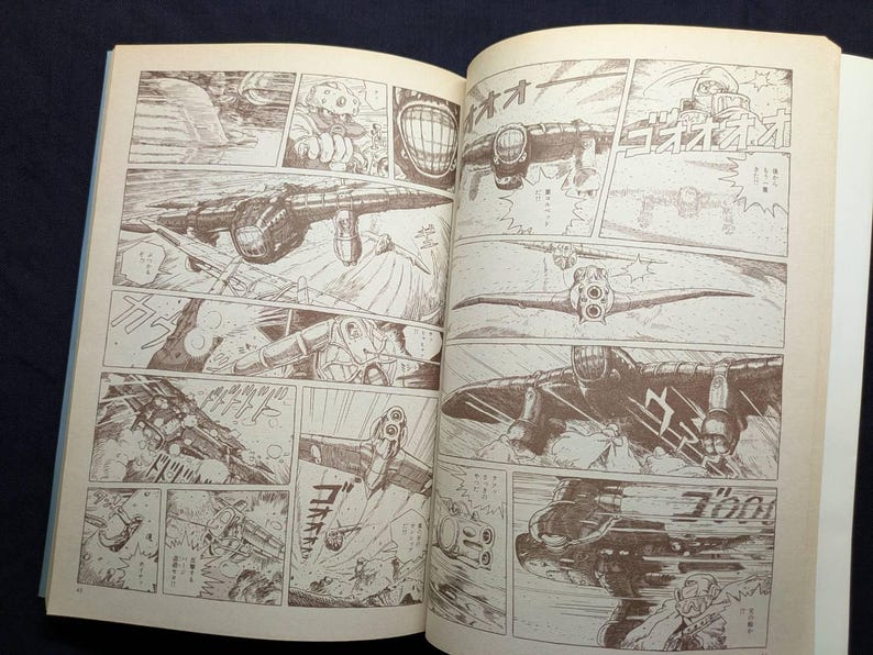 May include: Open book with sepia-toned illustrations. The artwork depicts a series of panels showing aircraft in flight and combat scenes. The style is reminiscent of a vintage comic book or manga.