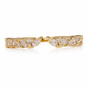 Puede incluir: Un anillo dorado con un diseño de caña dividida. El anillo está adornado con múltiples piedras preciosas claras, de talla marquesa. Las piedras están engastadas juntas, creando un brillo continuo. El anillo está sobre un fondo blanco.