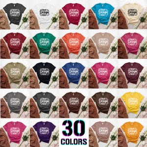 May include: A display of 30 different colored t-shirts, each with the text "Your Design Here" in a white script. The shirts are arranged in rows and columns, showcasing a variety of hues, including black, white, red, and blue.